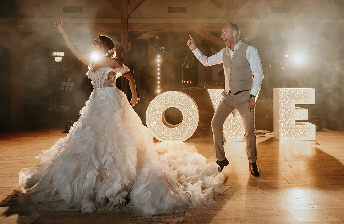 deux mariés en train de danser, avec des décors écrit love en arrière plan